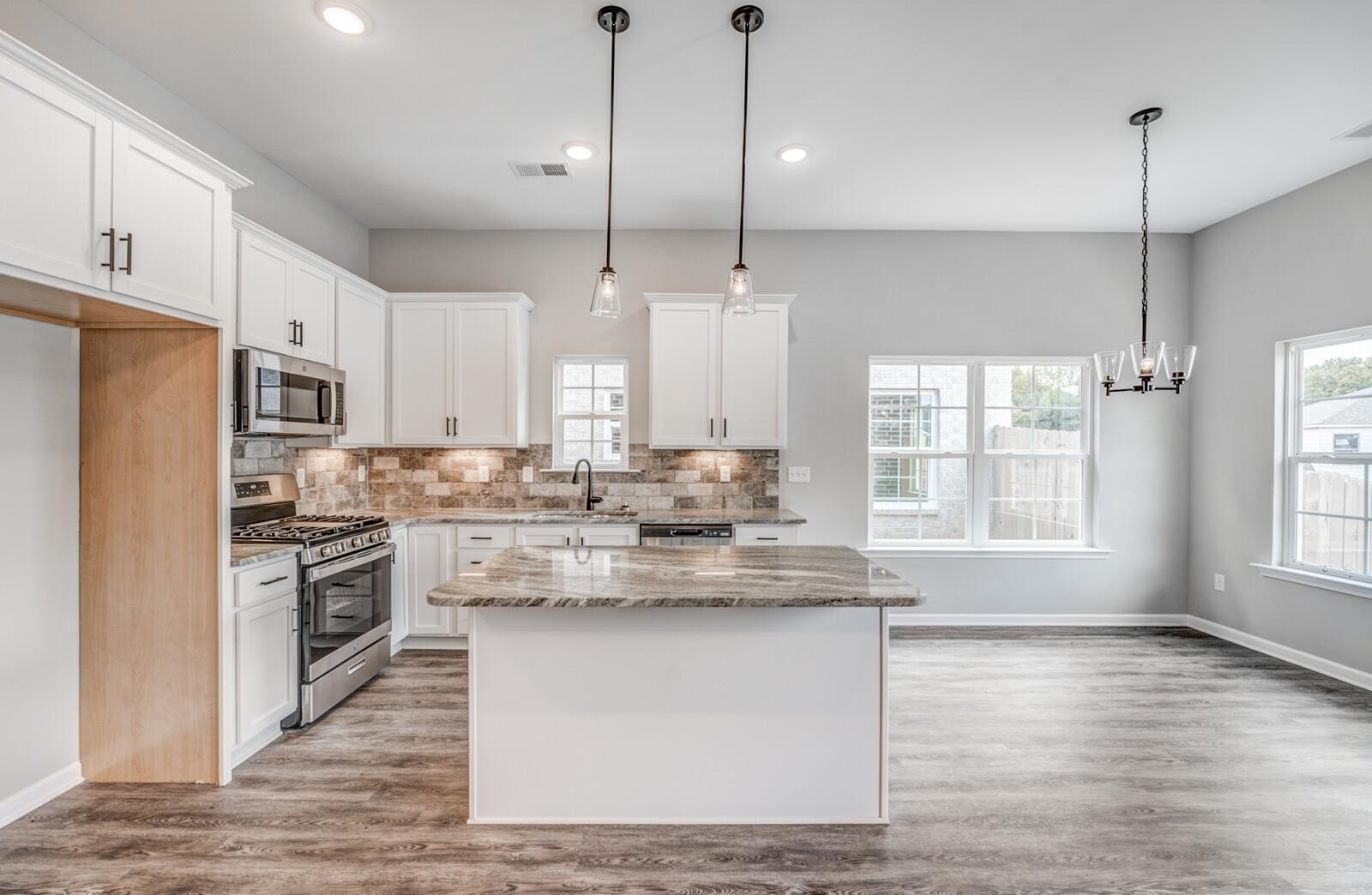 100 Blue Street Oakland, TN 38060 - Photo 13 of 40 a kitchen with kitchen island a sink a stove a refrigerator and white cabinets with wooden floor