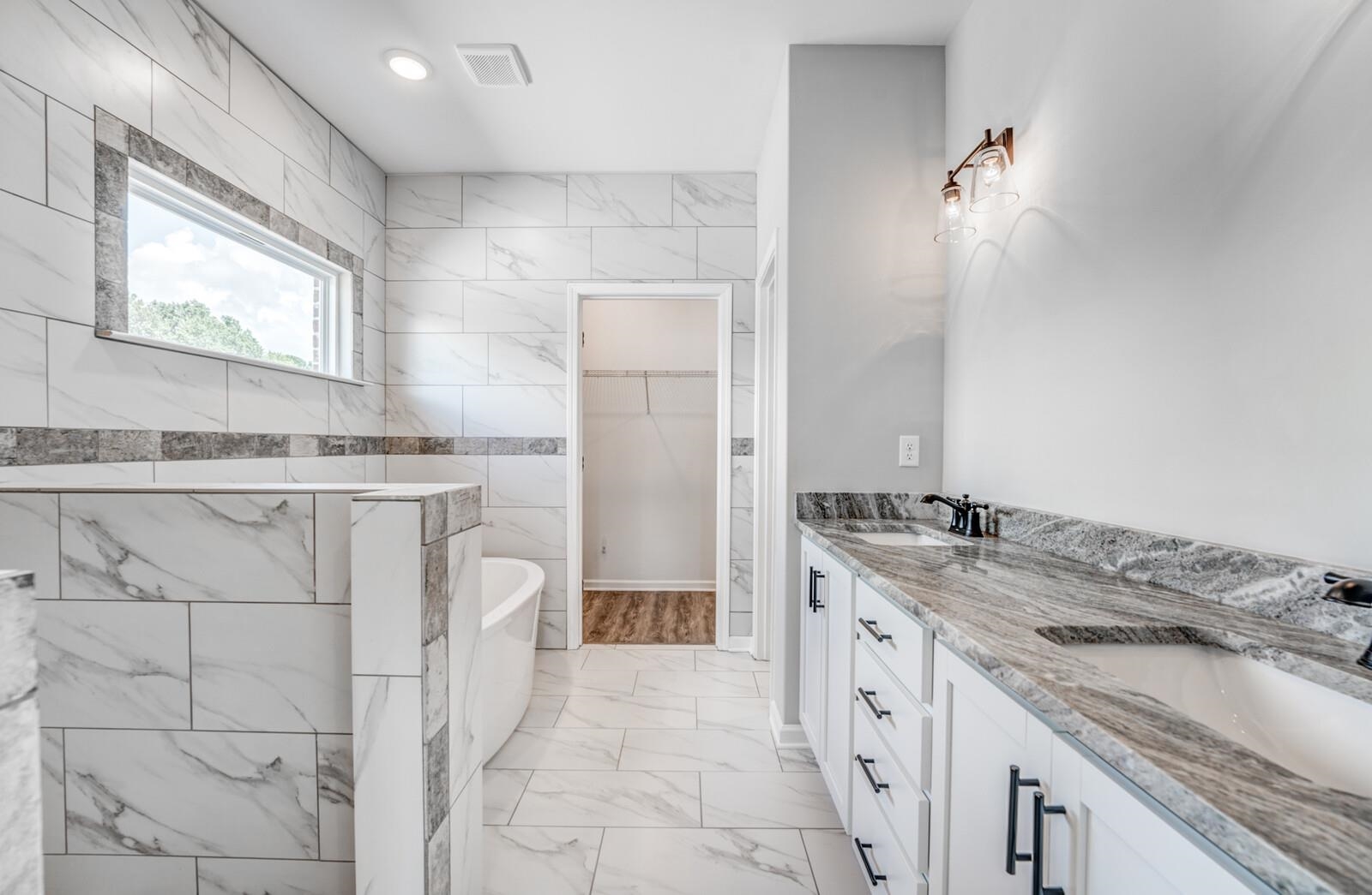 100 Blue Street Oakland, TN 38060 - Photo 22 of 40 a spacious bathroom with a granite countertop sink a mirror and a bathtub