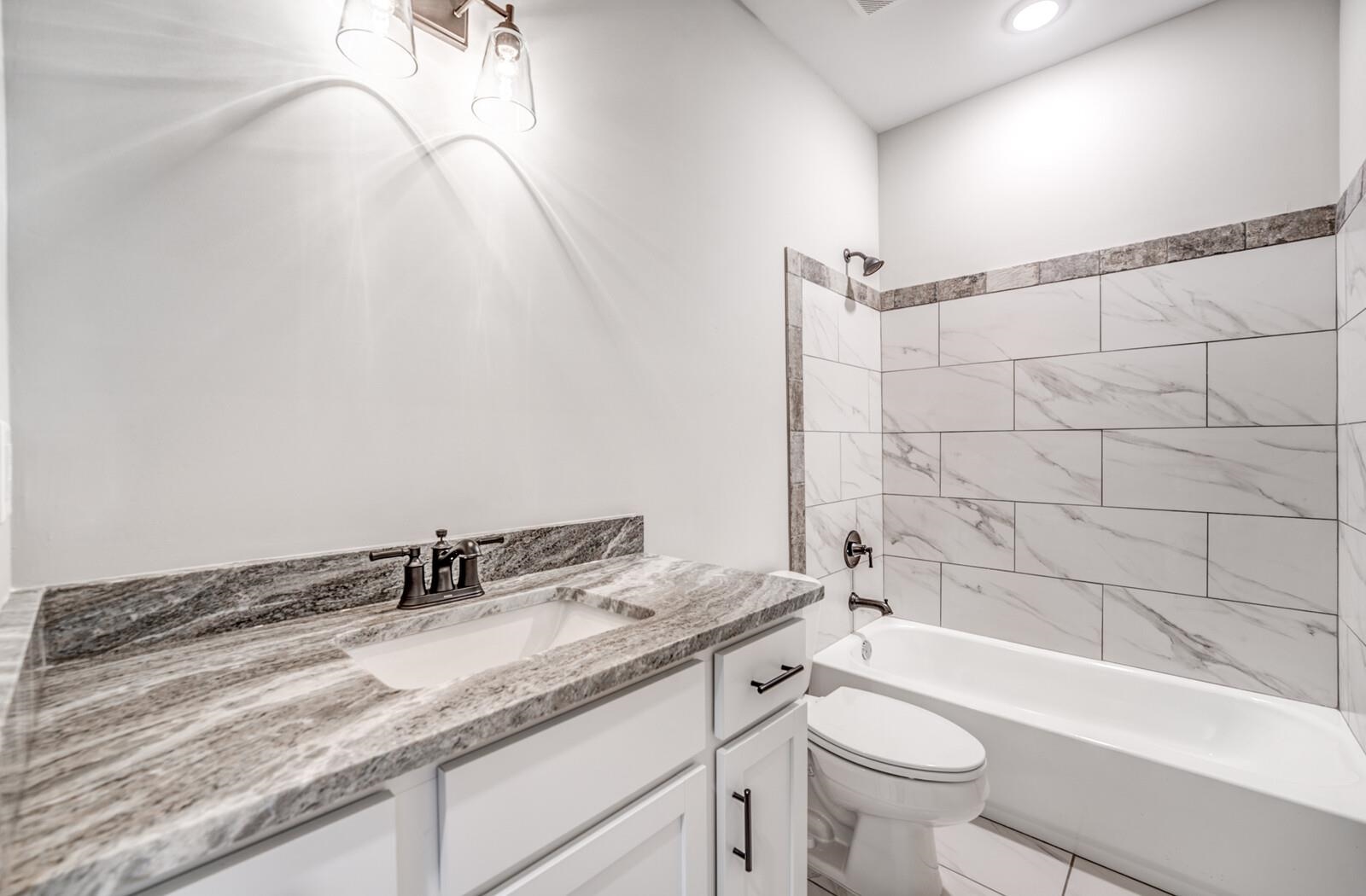 100 Blue Street Oakland, TN 38060 - Photo 28 of 40 a bathroom with a granite countertop sink a toilet and bathtub