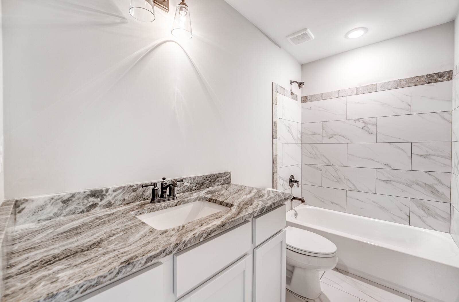 100 Blue Street Oakland, TN 38060 - Photo 31 of 40 a bathroom with a granite countertop sink a toilet and bathtub