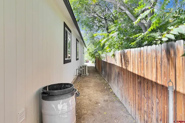 a view of a pathway of a house with a fountain and wooden fence