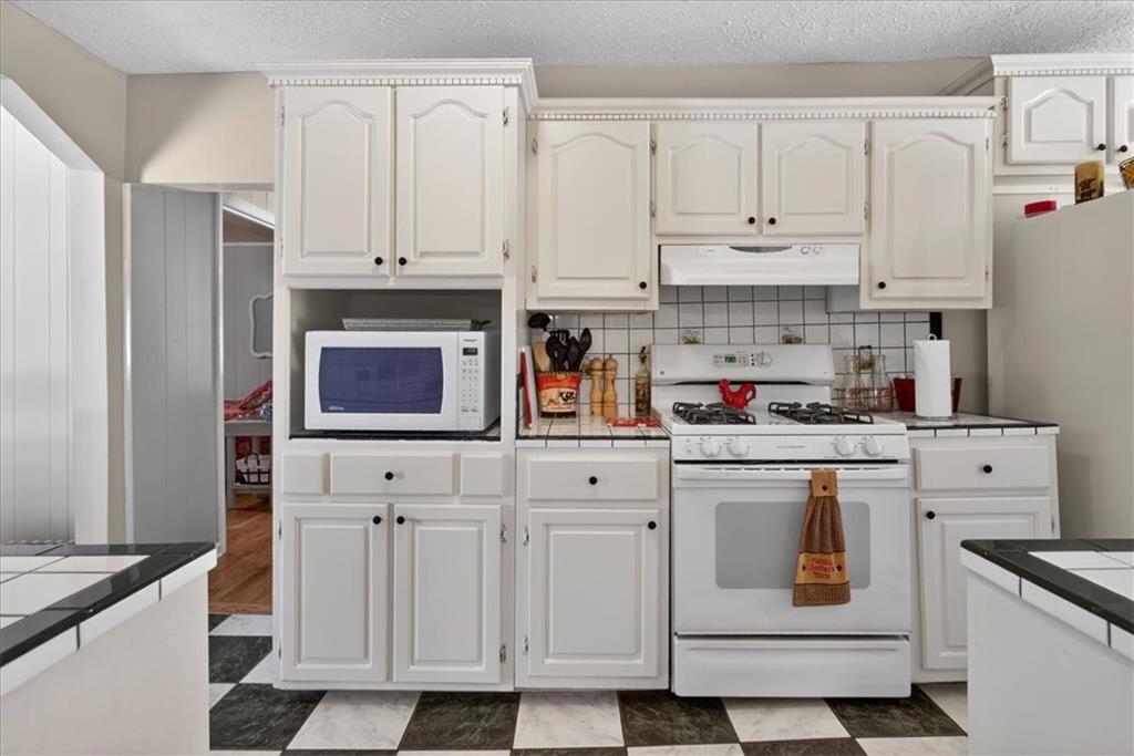 7433 Nicklesville Road Northeast Ranger, GA 30734 - Photo 16 of 53 a kitchen with stainless steel appliances granite countertop a stove and white cabinets