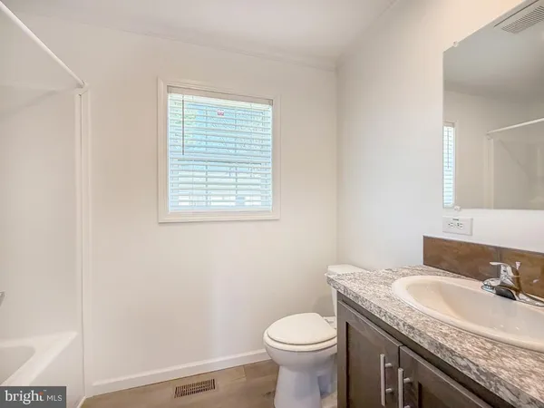 a bathroom with a granite countertop sink and a toilet