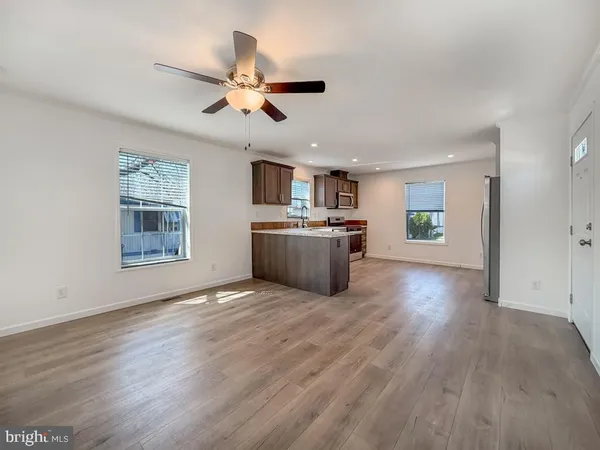 a view of a kitchen with a sink cabinet a ceiling fan and wooden floor