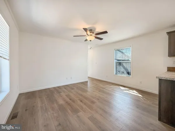 an empty room with wooden floor and ceiling fan
