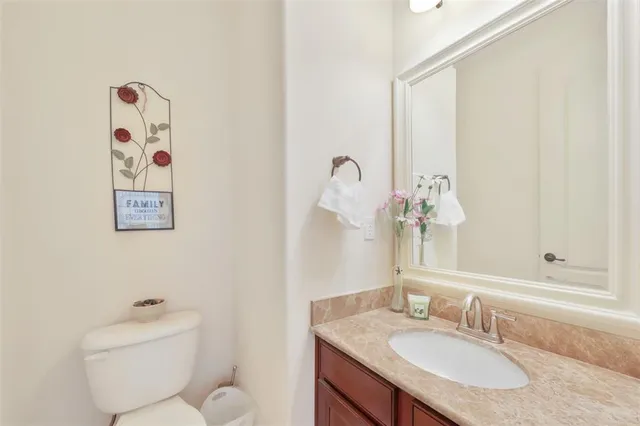a bathroom with a granite countertop sink a toilet and a mirror
