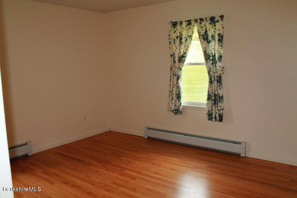 265 Yokun Road Richmond, MA 01201 - Photo 14 of 24 an empty room with wooden floor and windows