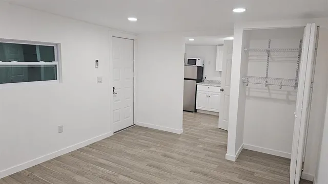 a view of a kitchen with a refrigerator and wooden floor