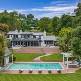 a view of pool with lawn chairs and large trees