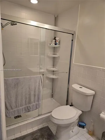 a white toilet sitting next to a shower
