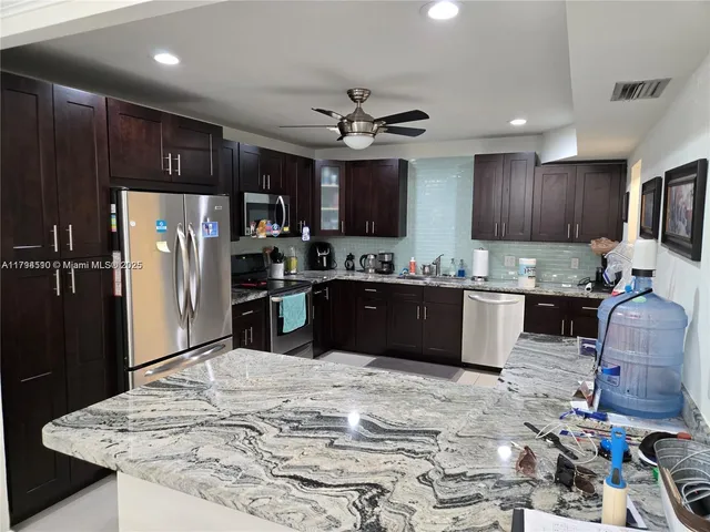 a kitchen with stainless steel appliances kitchen island granite countertop a refrigerator sink and cabinets