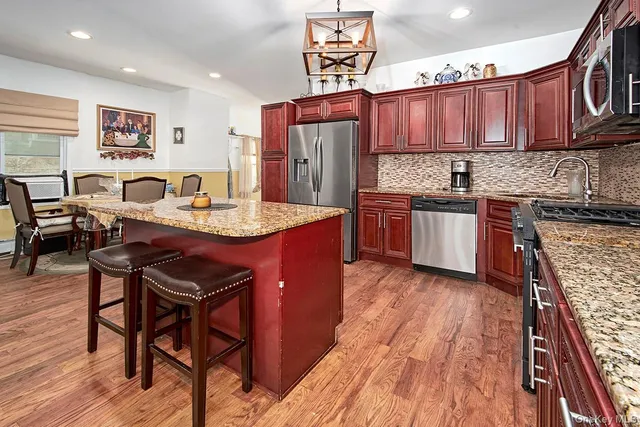 a kitchen with stainless steel appliances granite countertop wooden cabinets a stove a sink and a refrigerator