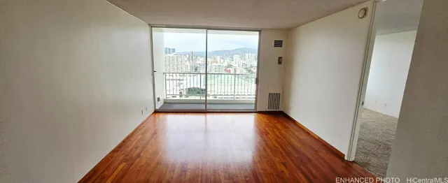 a view of an empty room with wooden floor and a window