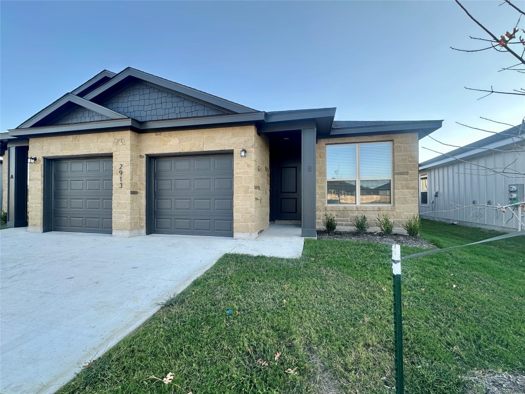 2913 Quail Rdg Lane, Unit B Temple, TX 76501 - Photo 1 of 20 View of front of home featuring a front yard, concrete driveway, an attached garage, and stone siding