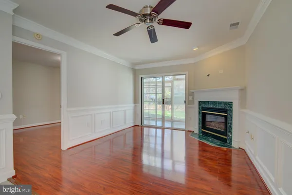 an empty room with wooden floor fan and windows