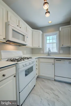 a kitchen with granite countertop white cabinets and white appliances
