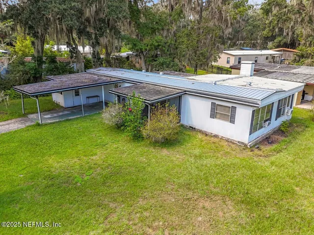 a view of a house with a big yard plants and large trees