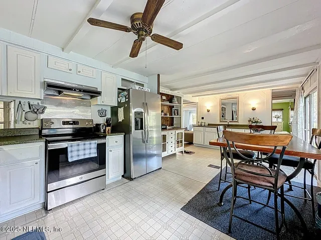 a kitchen with stainless steel appliances kitchen island granite countertop a table chairs and a refrigerator