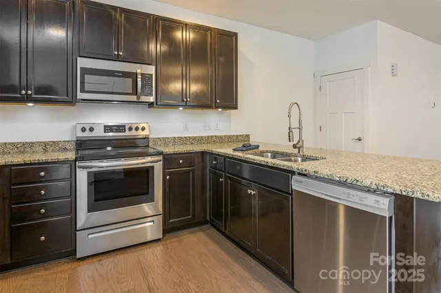 a kitchen with stainless steel appliances granite countertop wooden cabinets stove top oven and sink