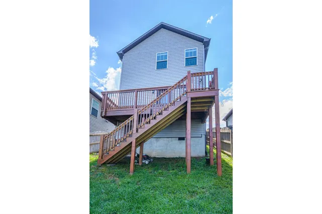 a view of a house with a yard plants and wooden fence