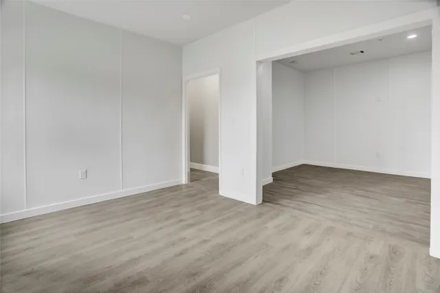 a view of an empty room with wooden floor and windows