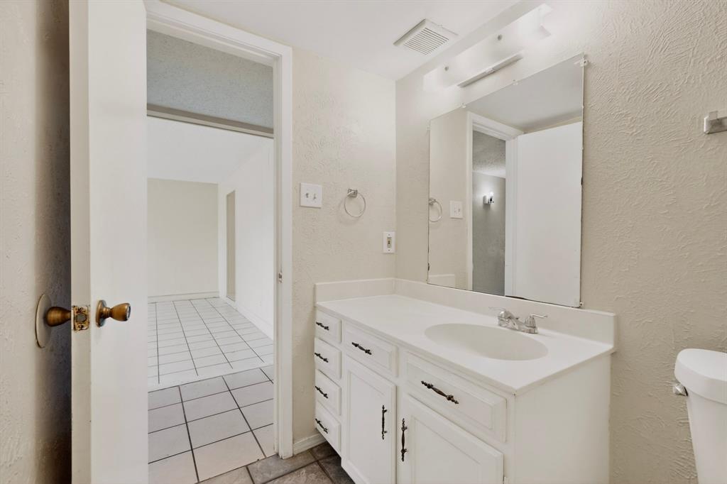 703 East Shady Grove Road Irving, TX 75060 - Photo 18 of 40 a bathroom with a sink a toilet and a mirror