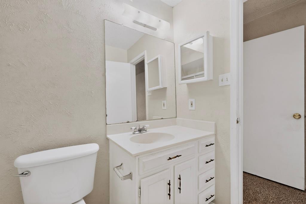 703 East Shady Grove Road Irving, TX 75060 - Photo 25 of 40 a bathroom with a sink a toilet and a mirror