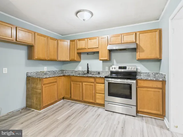 a kitchen with granite countertop wooden floors appliances and cabinets