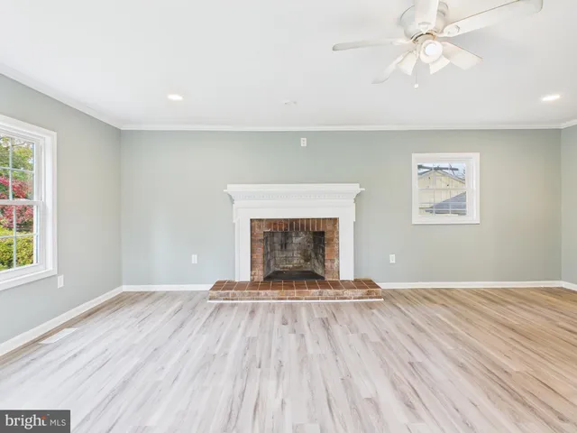 a view of an empty room with wooden floor fireplace and a window