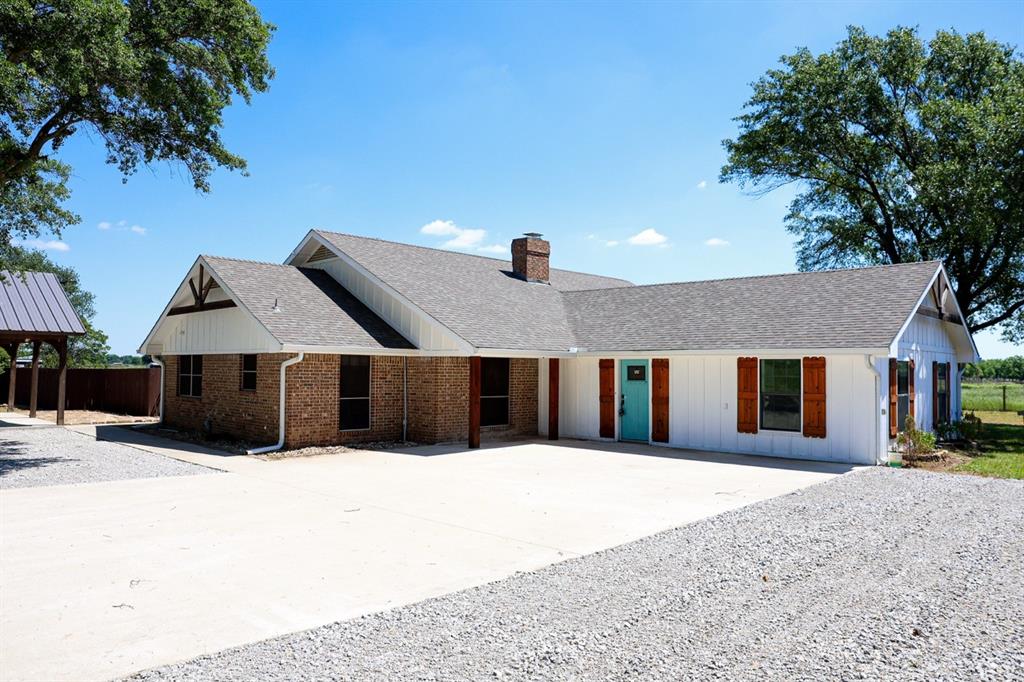 10575 Friendship Road Pilot Point, TX 76258 - Photo 3 of 32 Ranch-style exterior featuring a mix of brick and white vertical siding, a turquoise front door, and wooden shutters