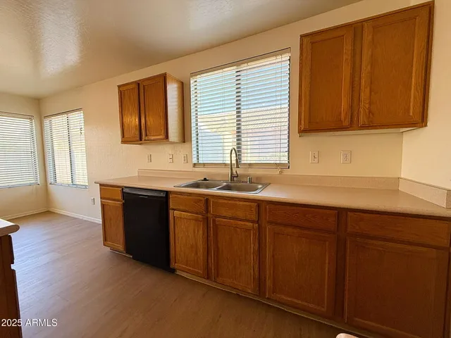 a kitchen with stainless steel appliances granite countertop wooden cabinets a sink and dishwasher with wooden floor