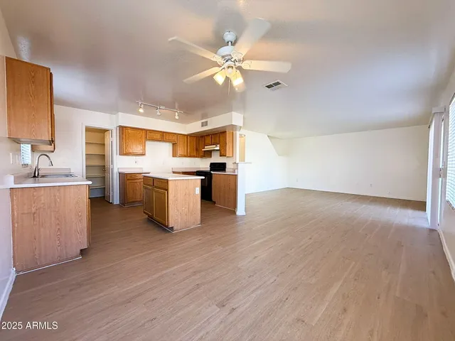 a view of a kitchen with a sink a stove top oven and cabinets