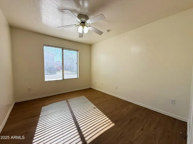 an empty room with wooden floor chandelier fan and windows