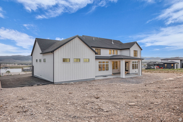 2828 Jojo Road Eagle Mountain, UT 84005 - Photo 55 of 63 Modern farmhouse-style residence featuring white vertical siding, black-trimmed windows, a covered patio, and dark shingle roofing