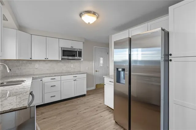 a kitchen with stainless steel appliances granite countertop a refrigerator a stove and a sink with wooden floor