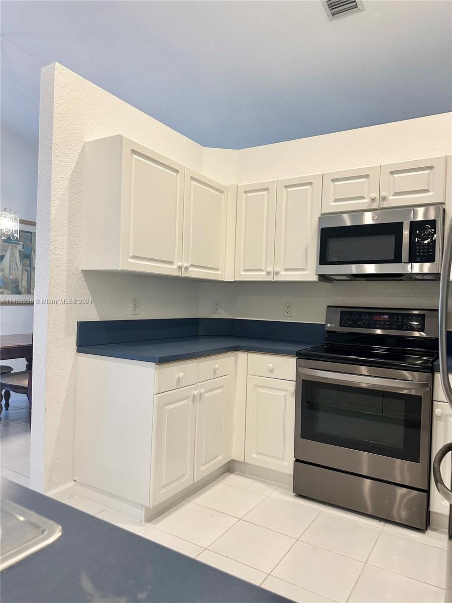 1509 Sunset Way Weston, FL 33327 - Photo 12 of 24 a kitchen with stainless steel appliances a stove microwave and refrigerator