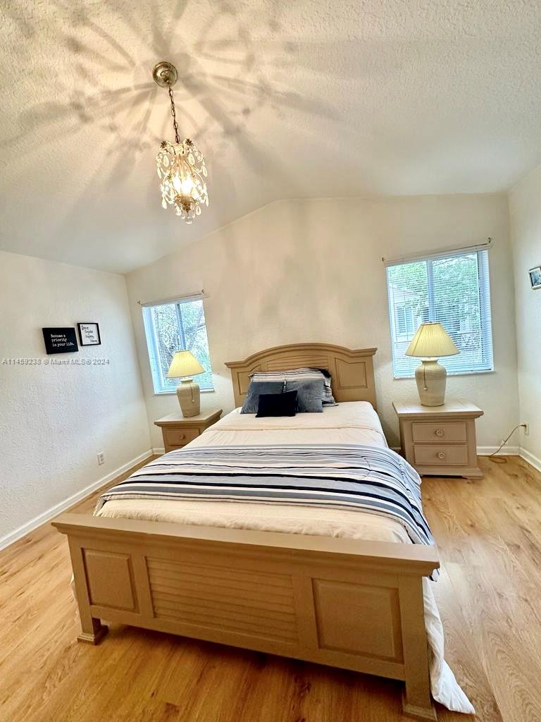 1509 Sunset Way Weston, FL 33327 - Photo 13 of 24 a spacious bedroom with a bed and chandelier
