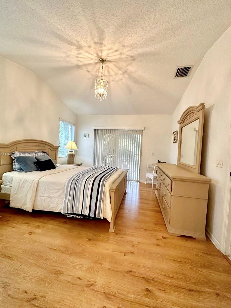 1509 Sunset Way Weston, FL 33327 - Photo 14 of 24 a bedroom with a bed and wooden floor