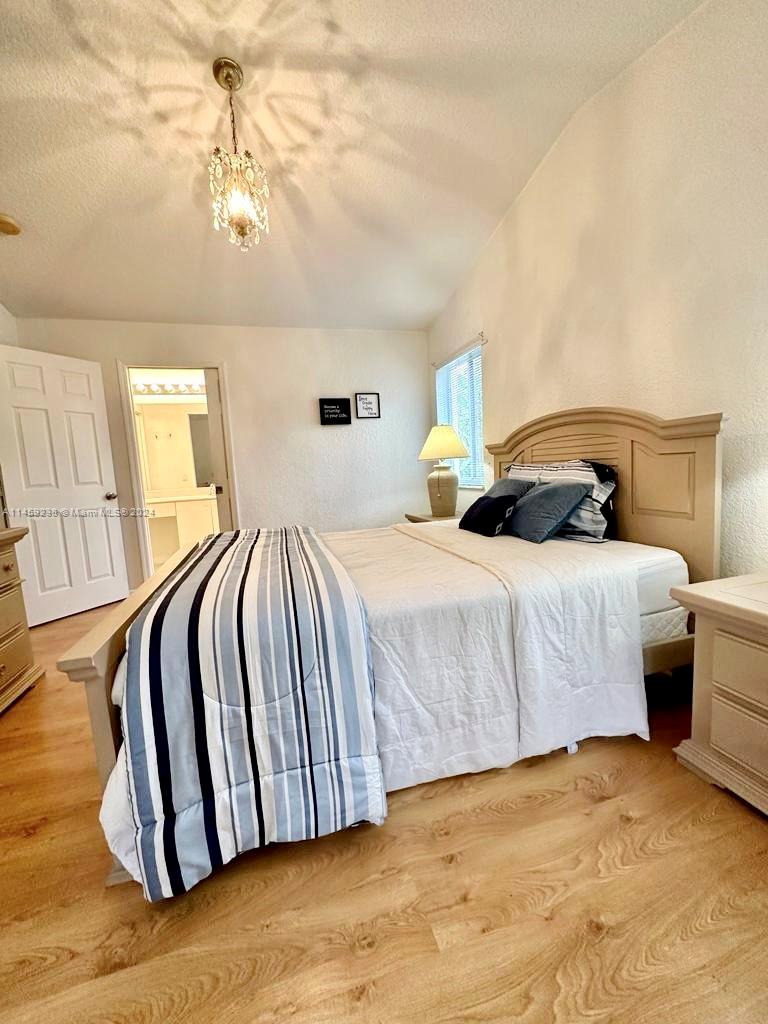 1509 Sunset Way Weston, FL 33327 - Photo 15 of 24 a bedroom with a bed and wooden floor