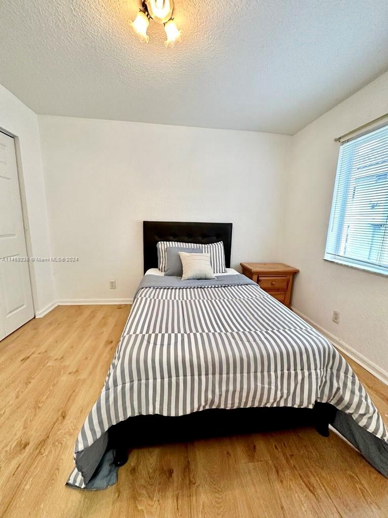 1509 Sunset Way Weston, FL 33327 - Photo 16 of 24 a bedroom with a bed and wooden floor