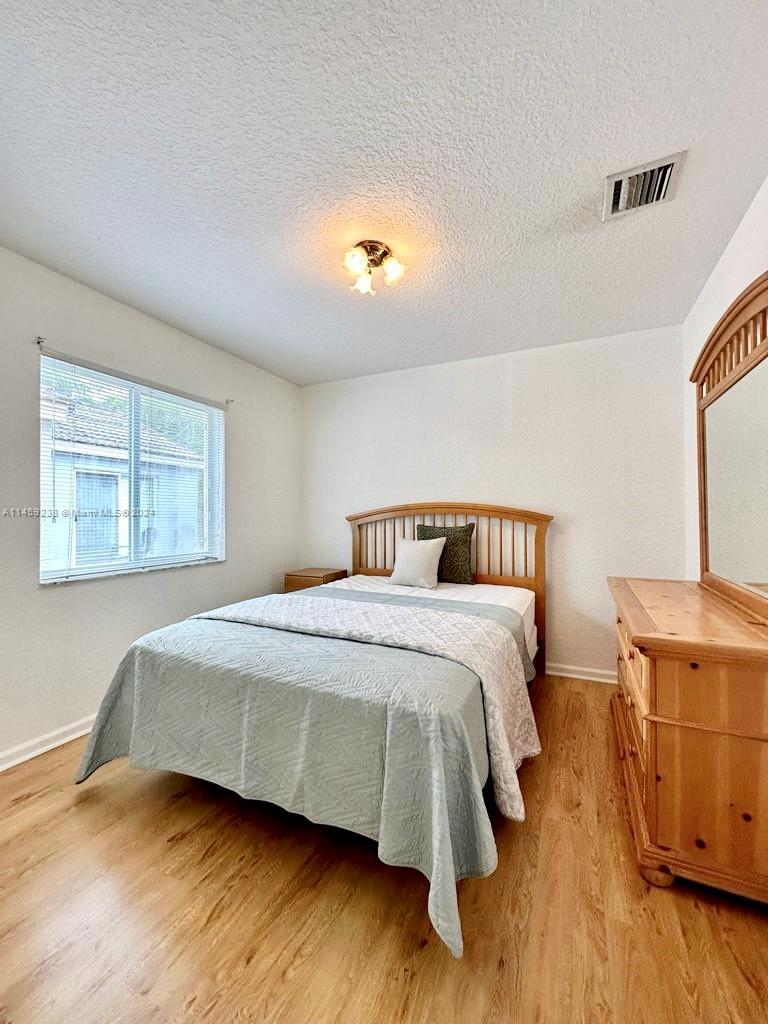 1509 Sunset Way Weston, FL 33327 - Photo 19 of 24 a bedroom with a bed and wooden floor
