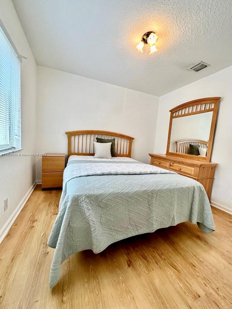 1509 Sunset Way Weston, FL 33327 - Photo 21 of 24 a bedroom with a bed and wooden floor