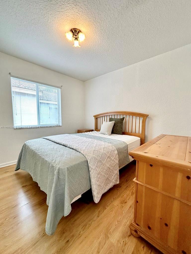 1509 Sunset Way Weston, FL 33327 - Photo 22 of 24 a bedroom with a bed and wooden floor