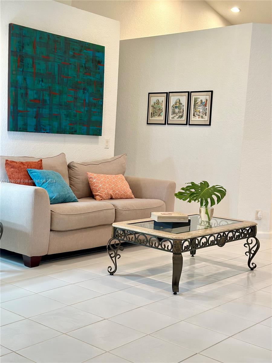 1509 Sunset Way Weston, FL 33327 - Photo 6 of 24 a living room with a couch and a potted plant on a dresser