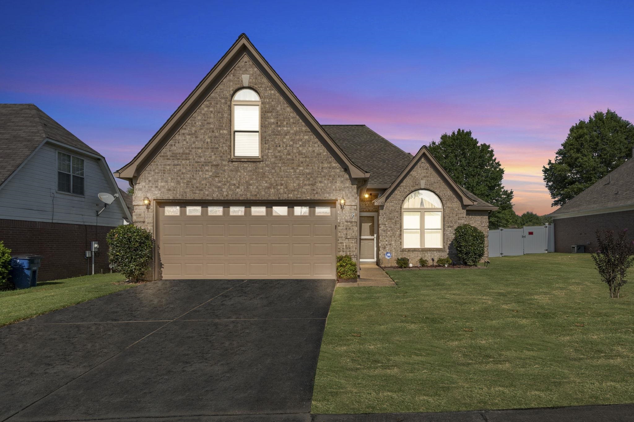 Traditional-style home with brick siding, concrete driveway, and a gate