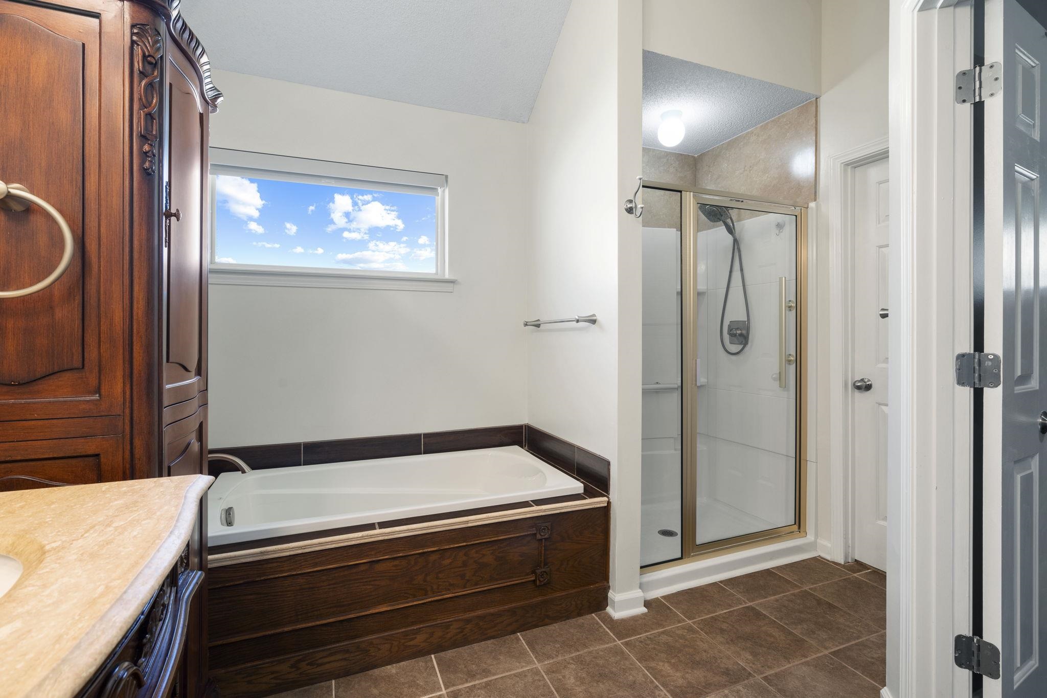 7232 Maple Grove Road Olive Branch, MS 38654 - Photo 15 of 18 Bathroom featuring vanity, a garden tub, a shower stall, dark tile patterned floors, and a textured ceiling