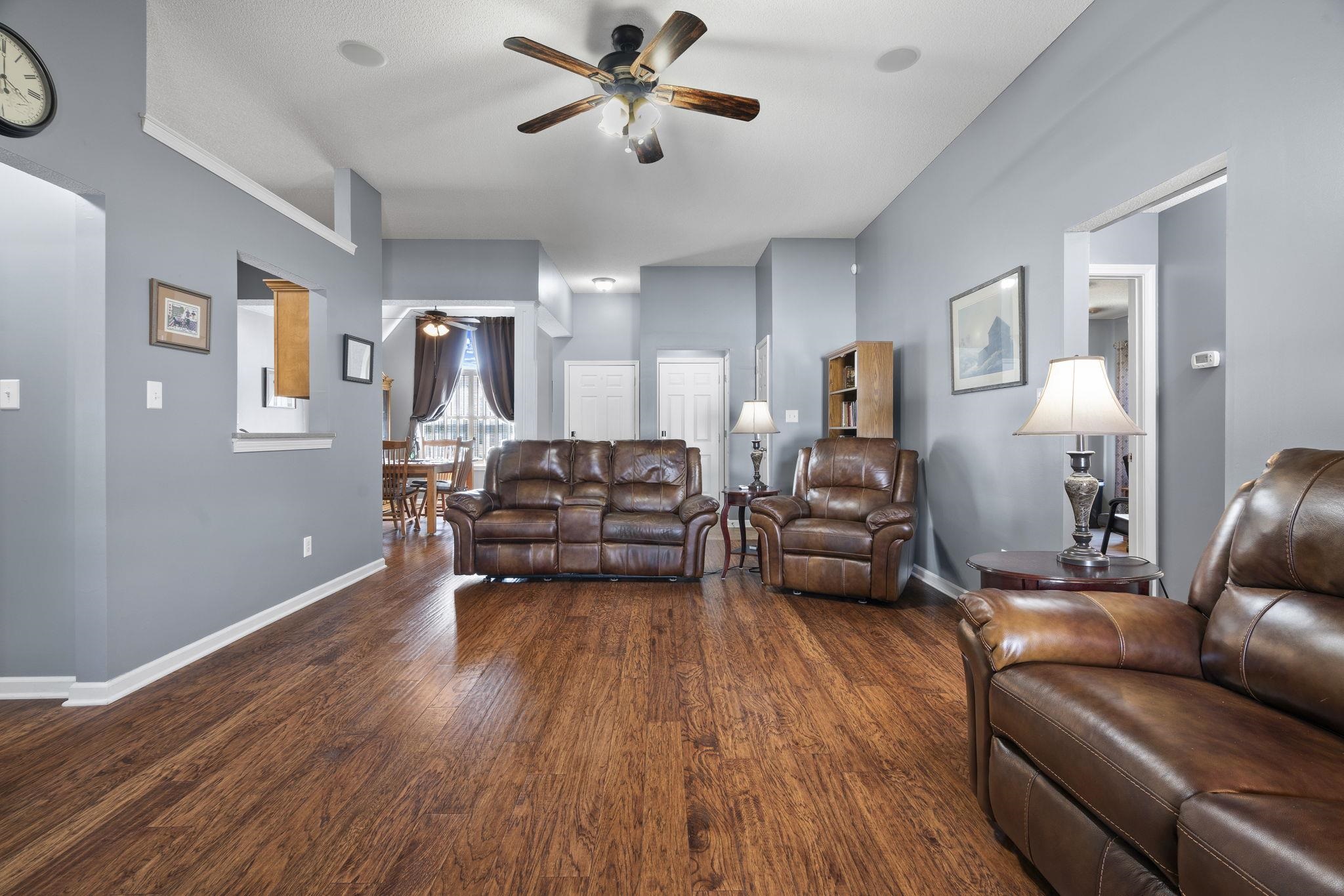 Living area featuring ceiling fan and dark wood-type flooring