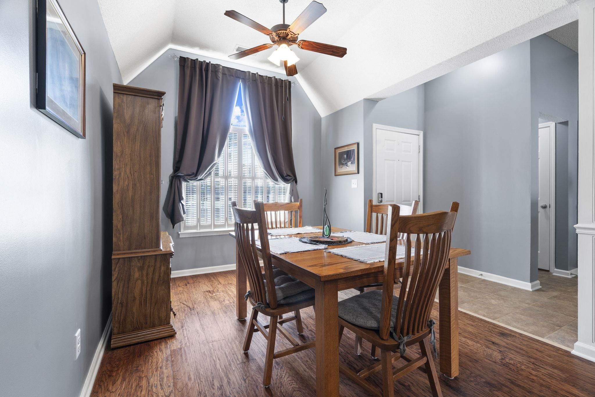 Dining room with wood finished floors, vaulted ceiling, and ceiling fan
