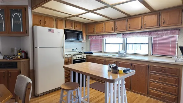 a kitchen with stainless steel appliances granite countertop a stove a sink dishwasher a refrigerator with wooden cabinets and floor