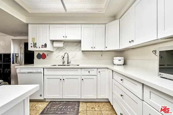 a kitchen with white cabinets and sink